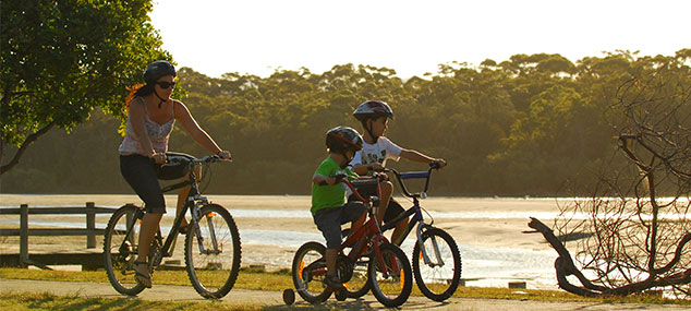 woman and children riding bicycles alongside a river