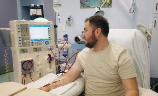 Patient sitting in hospital chair receiving dialysis through machine